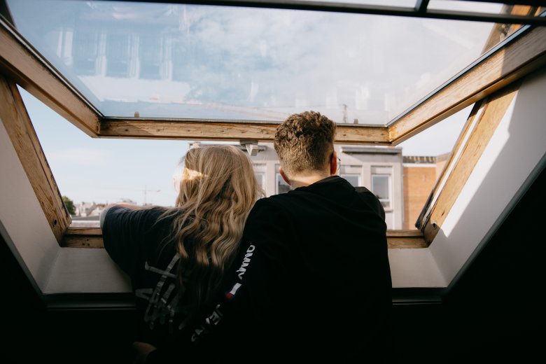 fille et garçon de dos regardant l'extérieur à travers un velux